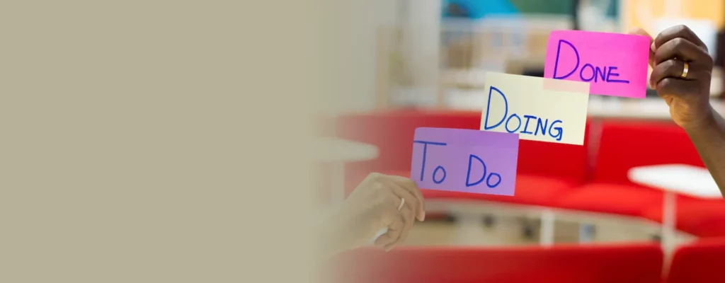 Hands holding colorful sticky notes with the words "to do," "doing," and "done" representing task progress stages.