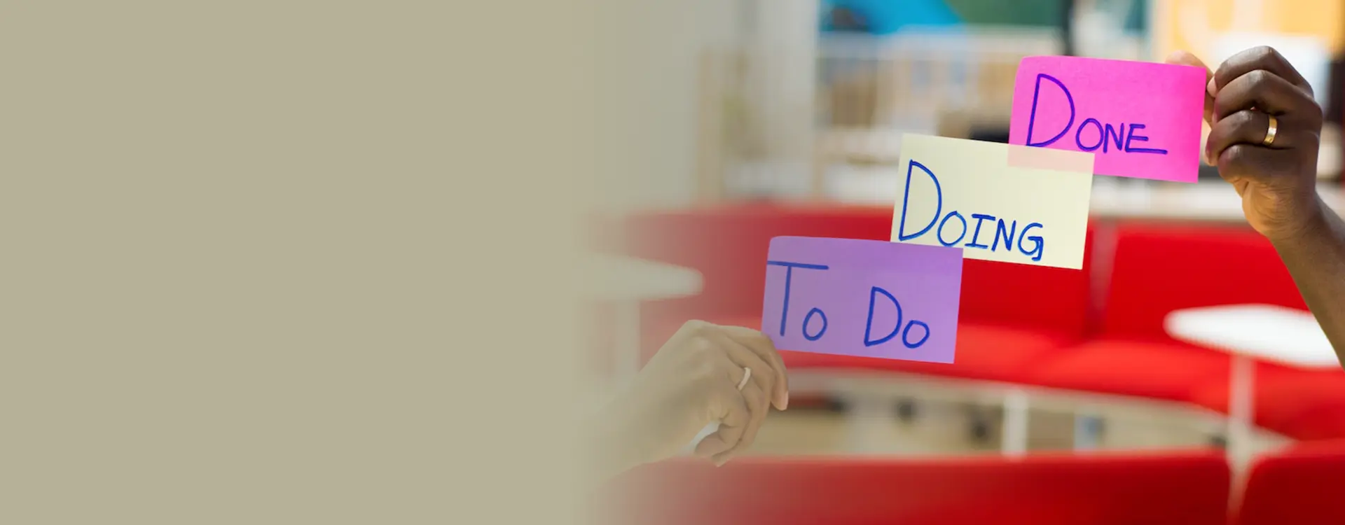 Hands holding colorful sticky notes with the words "to do," "doing," and "done" representing task progress stages.