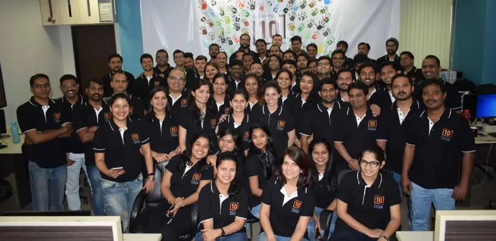 A group of enthusiastic Focalworks employees wearing matching shirts, gathered for a team photo in an office environment.