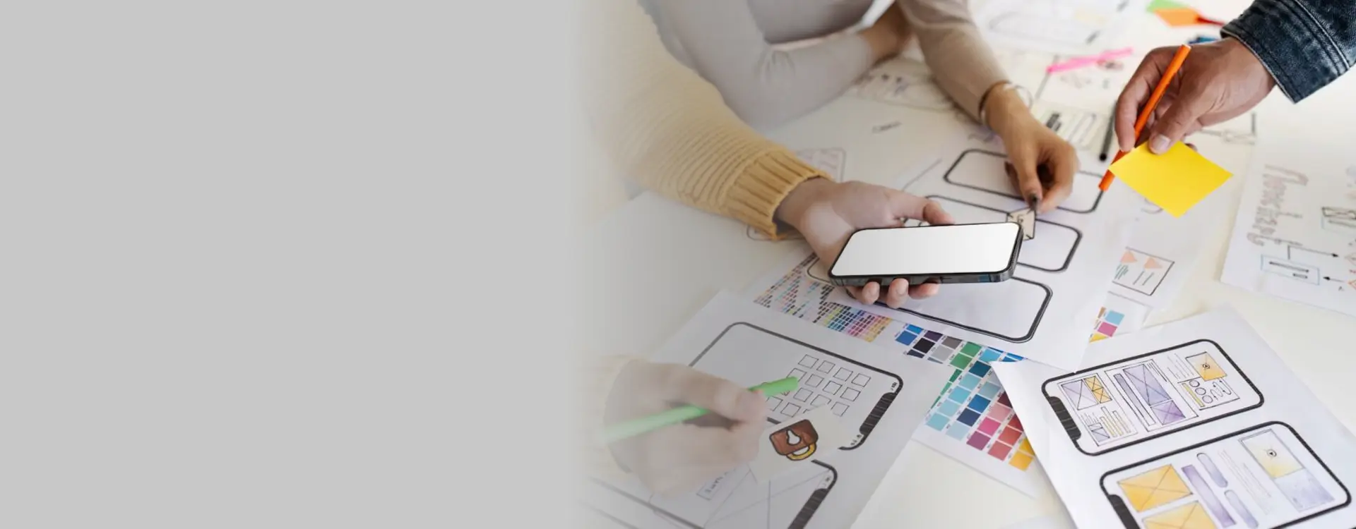 Team of professionals working on mobile app design, collaborating over color samples and wireframe sketches.