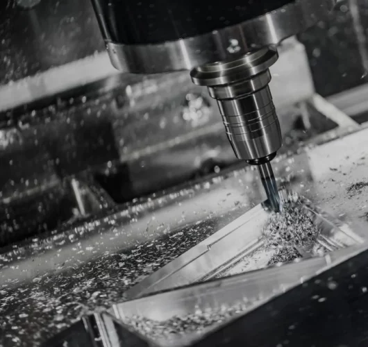 A CNC machine precisely cuts metal, with shiny swirls of shavings surrounding the tool. Sparks fly, conveying intense focus and industrial efficiency.